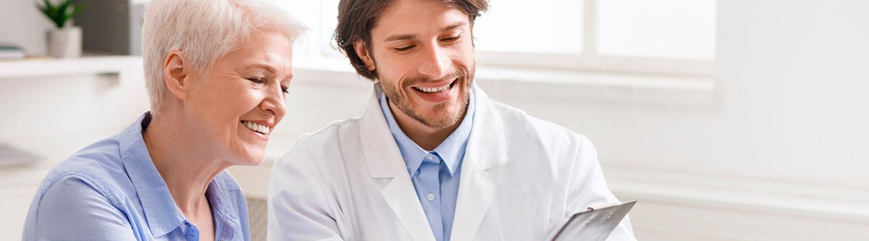 A male pharmacist is helping his patient to understand her medical conditions. The information is available on his clipboard.